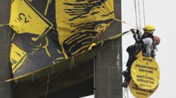 Aktivis Greenpeace Indonesia membentangkan spanduk kritik krisis iklim di Patung Selamat Datang, Bundaran HI, Jakarta, Selasa 20 Oktober 2026.