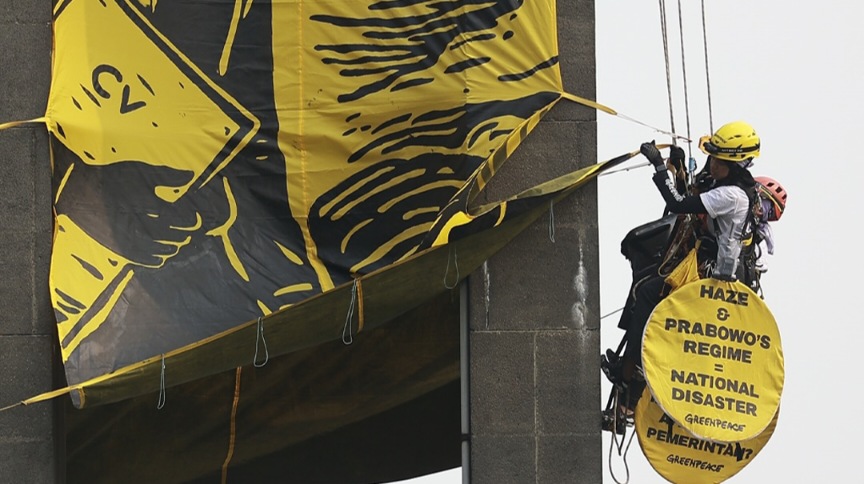 Aktivis Greenpeace Indonesia membentangkan spanduk kritik krisis iklim di Patung Selamat Datang, Bundaran HI, Jakarta, Selasa 20 Oktober 2026.