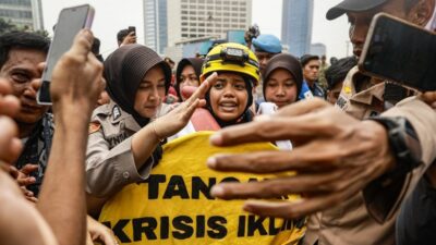 Aktivis Greenpeace Indonesia membentangkan spanduk kritik krisis iklim di Patung Selamat Datang, Bundaran HI, Jakarta, 20 Oktober 2026.
