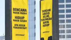 Aktivis Greenpeace Indonesia membentangkan spanduk kritik krisis iklim di Patung Selamat Datang, Bundaran HI, Jakarta, pada 20 Oktober 2026.