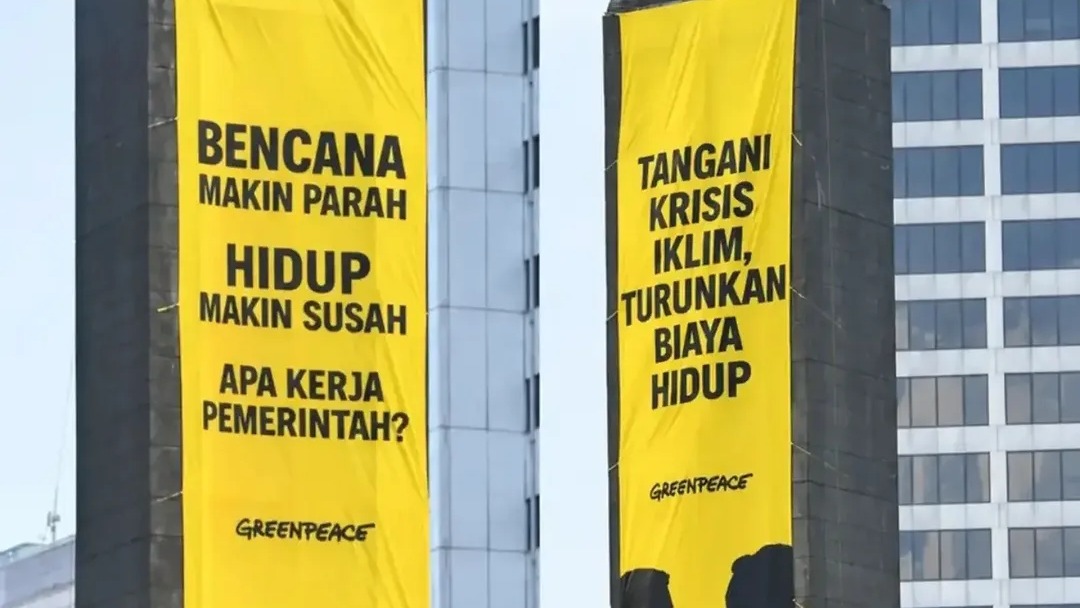 Aktivis Greenpeace Indonesia membentangkan spanduk kritik krisis iklim di Patung Selamat Datang, Bundaran HI, Jakarta, pada 20 Oktober 2026.